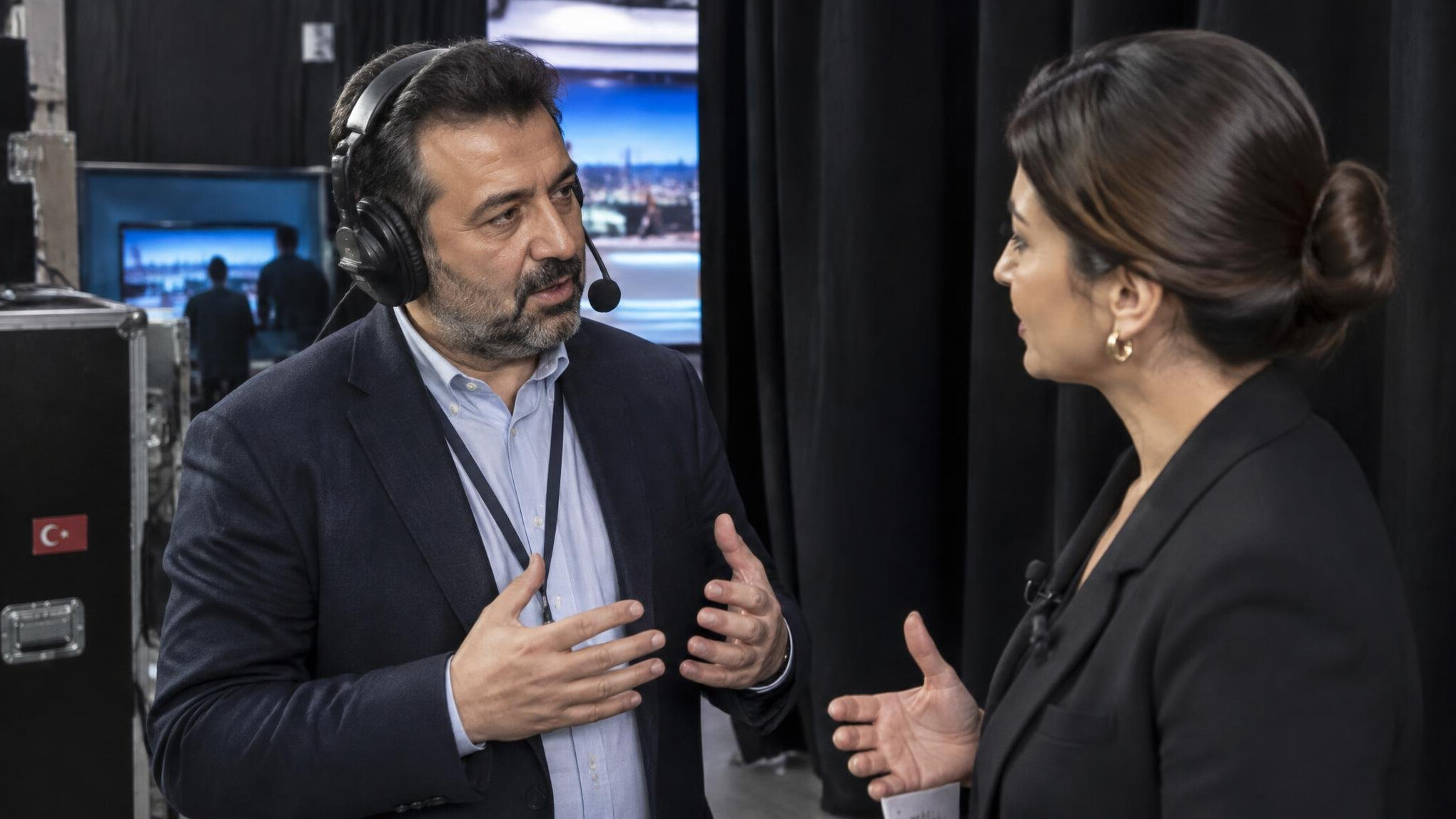 Crisis mediator speaking calmly with a TV presenter backstage